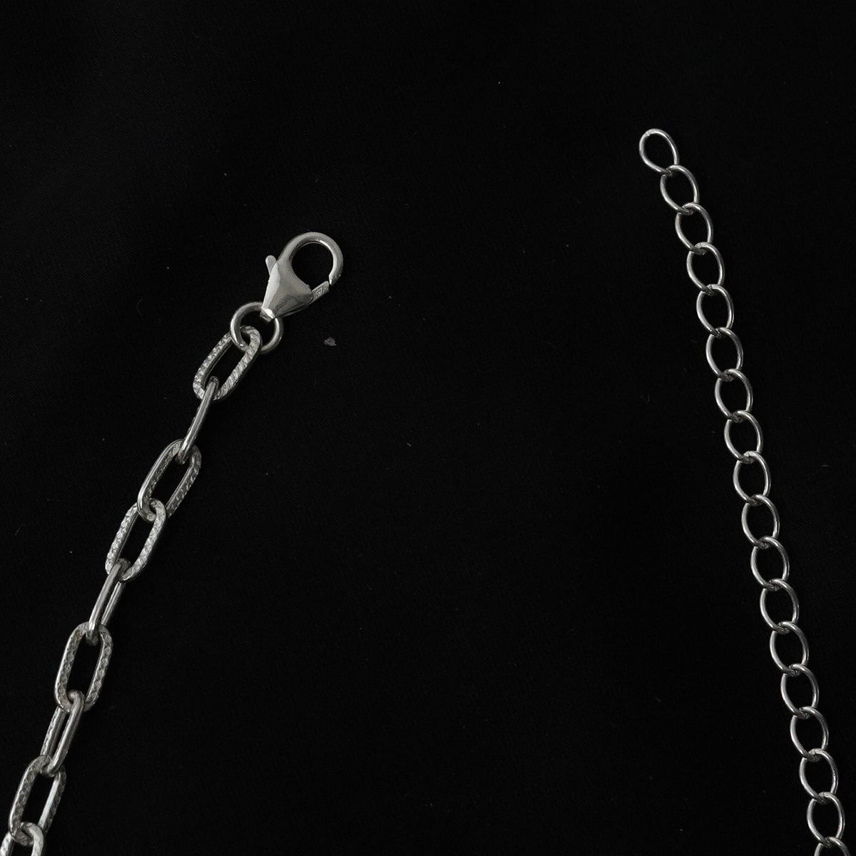 925 Silver metal chain extender with a lobster clasp and elongated links, shown on a black background.