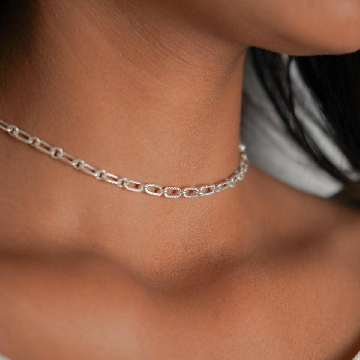 A close-up of a model wearing a delicate 925 silver paperclip chain choker necklace.