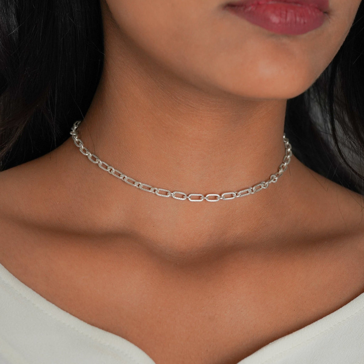 A Front View of a model wearing a delicate 925 silver chain choker necklace with elongated oval links, paired with a white top.
